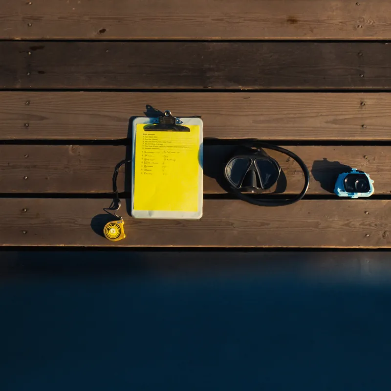 Inspection toolkit flat lay with dive mask, clipboard, underwater camera, and tape measure