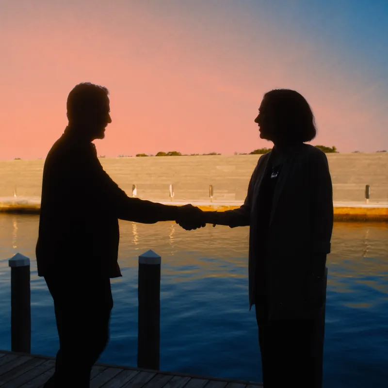 Handshake silhouette between contractor and homeowner on a finished Miami dock at sunset